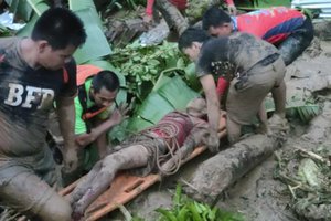 In this photo provided by the Philippine Coast Guard, a man is carried after being rescued from a landslide at Baybay City, Leyte province, central Philippines Monday April 11, 2022