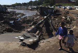 Children walk on damaged road at an informal settlement in Durban, South Africa, Thursday, April 14, 2022