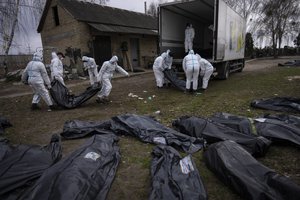 Volunteers load bodies of civilians killed in Bucha onto a truck to be taken to a morgue for investigation, in the outskirts of Kyiv, Ukraine, Tuesday, April 12, 2022.