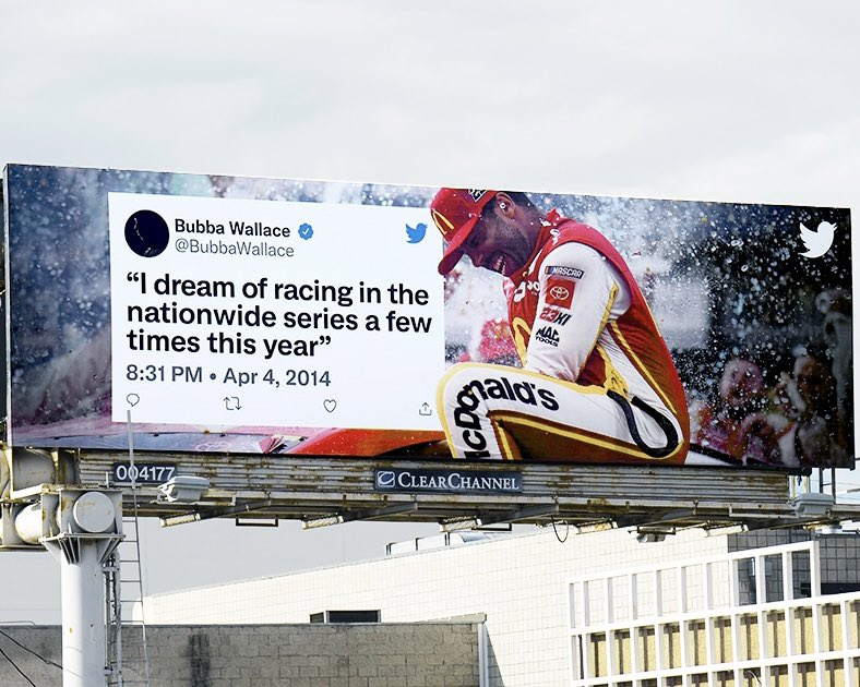 Image of a billboard in Los Angeles of a Tweet from Bubba Wallace that reads "I dream of racing in the nationwide series a few times this year" from April 2014. The Tweet is overlaid on an image of him  celebrating a win. 