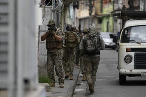 A special forces military police officer aims his weapon during an operation against alleged drug traffickers in the Vila Cruzeiro favela of Rio de Janeiro, Brazil, Friday, Feb. 11, 2022.