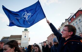 A man waves a blue flag in a crowd