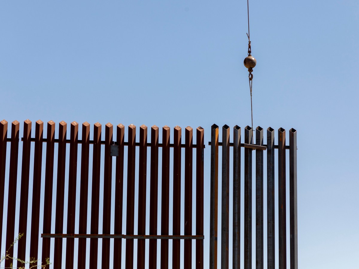 A crane lowers a section of the US/Mexico border wall into place.