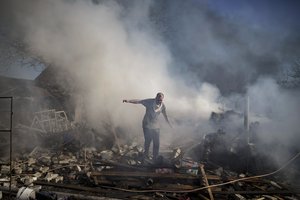 A neighbour walks on the debris of a burning house, destroyed after a Russian attack in Kharkiv, Ukraine, Thursday, March 24, 2022