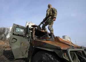 File - A Ukrainian soldier stands a top a destroyed Russian APC after recent battle in Kharkiv, Ukraine, on March 26, 2022. With Russia continuing to strike and encircle urban populations, from Chernihiv and Kharkiv in the north to Mariupol in the south, Ukrainian authorities said Saturday that they cannot trust statements from the Russian military Friday suggesting that the Kremlin planned to concentrate its remaining strength on wresting the entirety of Ukraine's eastern Donbas region from Ukrainian control