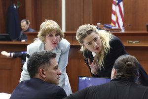 Actor Amber Heard speaks with her legal team as actor Johnny Depp returns to the stand after a lunch recess at the Fairfax County Circuit Court in Fairfax, Va., Thursday, April 21, 2022.