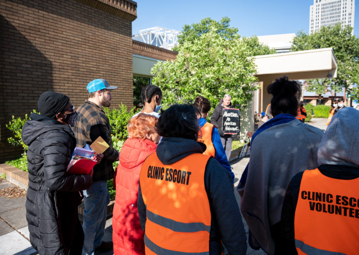 Photo of clinic volunteers watching an anti-abortion protester