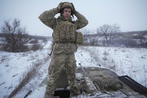 File - An Ukrainian serviceman adjusts his helmet atop an armored personnel carrier driving near front line position in the Luhansk area, eastern Ukraine, Friday, Jan. 28, 2022.