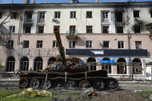 A destroyed tank and damaged during heavy fighting apartment building are seen in an area controlled by Russian-backed separatist forces in Mariupol, Ukraine, Tuesday, April 26, 2022.