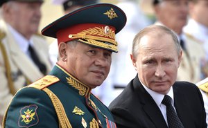 Vladimir Putin, right, listens to Defence Minister Sergei Shoigu as they attend the military parade during the Navy Day celebration in St. Petersburg, Russia