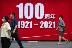 People walk past a partially disassembled exhibition commemorating the 100th anniversary of China’s Communist Party at a shopping and office complex in Beijing, Friday, July 2, 2021, China