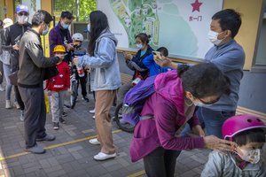 People wearing face masks check their smartphones to show proof of a negative COVID-19 test within the past 48 hours as they enter a public park in Beijing, Saturday, April 30, 2022, the first day of the Labor Day holiday period in China.