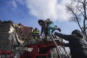 Firefighters help a woman to evacuate from a damaged by shelling apartment building in Mariupol, Ukraine, Thursday, March 10, 2022.