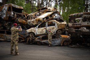 A territorial defence man poses for a photo next to cars destroyed during the Russian occupation in Irpin, on the outskirts of Kyiv, on Saturday, May 7, 2022.