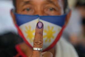 Raul Bragais, 64, shows the ink on his finger to mark that he has finished voting during the opening of elections on Monday May 9, 2022 in Quezon City, Philippines