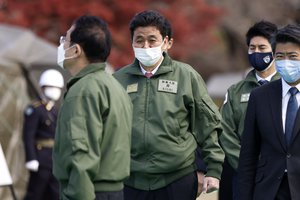 Japan's Defense Minister Nobuo Kishi, center, walks as he inspects weapons with Prime Minister Fumio Kishida, left, during a review at the Japan Ground Self-Defense Force Camp Asaka in Tokyo, Japan, Saturday, Nov. 27, 2021