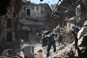 Donetsk People Republic Emergency Situations Ministry employees clear rubble at the side of the damaged Mariupol theater building during heavy fighting in Mariupol, in territory under the government of the Donetsk People's Republic, eastern Ukraine, Thursday, May 12, 2022.