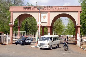 A man rides a motorbike taxi past police vehicles at the entrance of Shehu Shagari College of Education in Sokoto Nigeria, Friday, May 13, 2022.