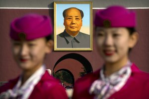 Hospitality staff members pose for a group photo near the large portrait of Chairman Mao on Tiananmen Gate before the closing ceremony of China's 19th Party Congress at the Great Hall of the People in Beijing, Tuesday, Oct. 24, 2017. China's ruling Communist Party moved Tuesday to confirm Xi Jinping's rise to becoming the country's most powerful leader in decades by amending its constitution to add his name and ideology. (AP Photo/Mark Schiefelbein)