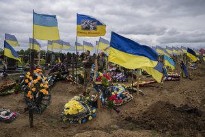 Two national guard soldiers drink a shot to honor the memory of two late soldiers in Kharkiv cemetery, eastern Ukraine, Sunday, May 22, 2022.