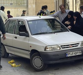 In this photo provided by Islamic Republic News Agency, IRNA, family members of Col. Hassan Sayad Khodayari weep over his body at his car after being shot by two assailants in Tehran, Iran, Sunday, May 22, 2022. Hassan Sayad Khodayari, a senior member of Iran's powerful Revolutionary Guard, was killed outside his home in Tehran on Sunday by unidentified gunmen on a motorbike, state TV reported.