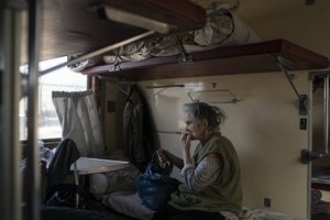 File - An elderly woman sits in a wagon sitting at a train station in Pokrovsk, Ukraine, Monday, April 25, 2022, before departing as she flees the war in Severodonetsk and nearby towns.