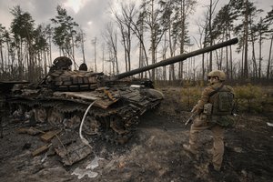 A Ukrainian serviceman stands next to a destroyed Russian tank after Ukrainian forces overran a Russian position outside Kyiv, Ukraine, Thursday, March 31, 2022