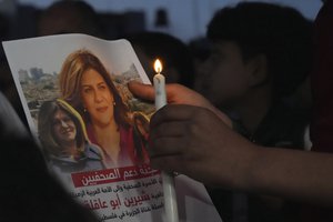 Palestinian holds a light candle and a picture of slain Al Jazeera journalist Shireen Abu Akleh, to condemn her killing, in front of the office of Al Jazeera network, in Gaza City, Wednesday, May 11, 2022