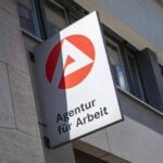 A masked woman walking in front of an employment agency in Berlin.