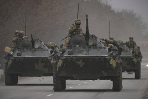 Ukrainian servicemen sit atop armored personnel carriers driving on a road in the Donetsk region, eastern Ukraine, Thursday, Feb. 24, 2022