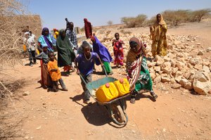 File - Faadomo Hirsi and her grandson wheel their daily allowance of two 20-litre jerrycans back to their house, Somaliland. Faadomo’s husband died a few years ago and she now looks after seven people – her children, grandchildren and her elderly mother.