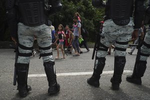 Migrants walk past members of the Mexican National Guard on their way north on the Huixtla road in Chiapas state, Mexico, Wednesday, June 7, 2022.