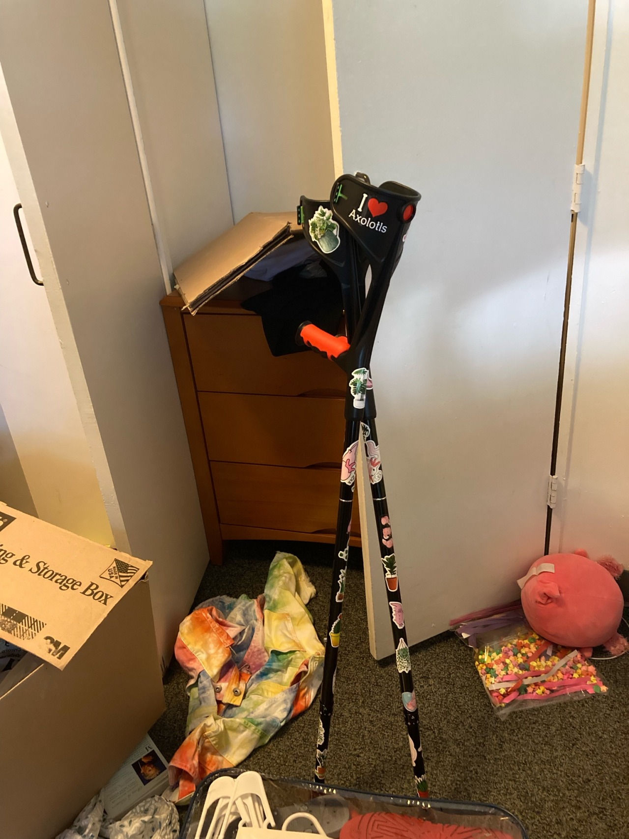 two black forearm crutches covered in stickers leaned up against a wall