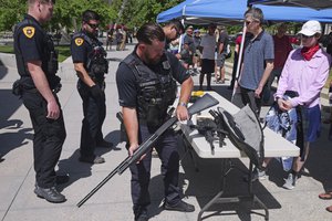 A Salt Lake City Policeman receives a gun during a buyback for those who wanted to take their firearms out of circulation Saturday, June 11, 2022, in Salt Lake City. The gun-buyback event at the Salt Lake City Police Department is an effort to get guns off the streets following a series of mass shootings across the U.S. in recent weeks.