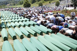 Bosnian people saying their prayer in front coffins during a funeral ceremony for the 127 victims at the Potocari memorial complex near Srebrenica