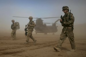 FILE - U.S. soldiers part of the NATO- led International Security Assistance Force (ISAF) walks, as a U.S. Chinook helicopter is seen on the back ground near the place where the foundation of a hospital was laid in Shindand, Herat, west of Kabul, Afghanistan, Saturday, Jan. 28, 2012.