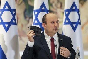 Israeli Prime Minister Naftali Bennett takes off his face mask as he chairs the weekly cabinet meeting at the Knesset in Jerusalem Monday, July 19, 2021.