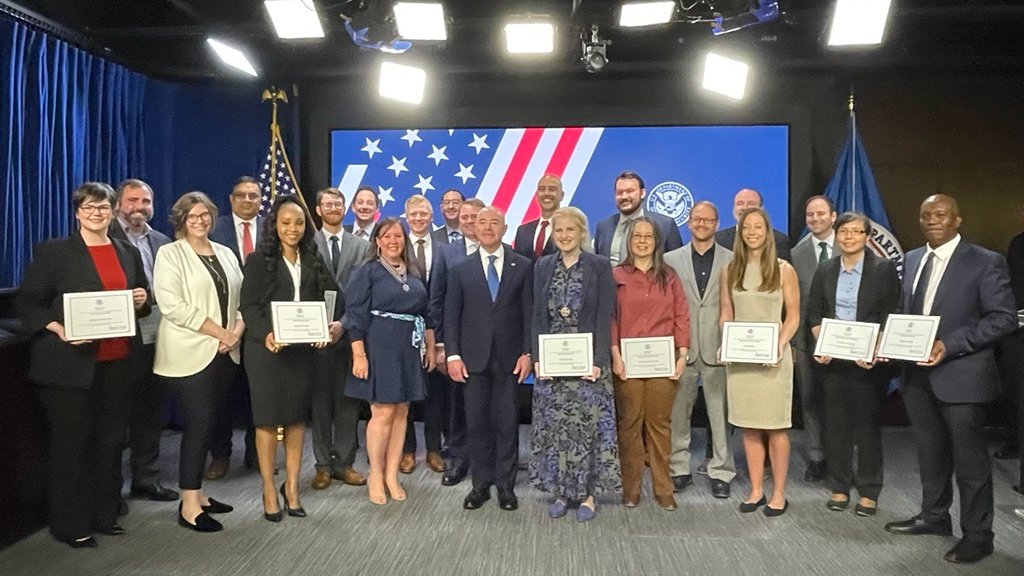 CISA team members pose with Secretary Mayorkas after receiving a Secretary award from DHS