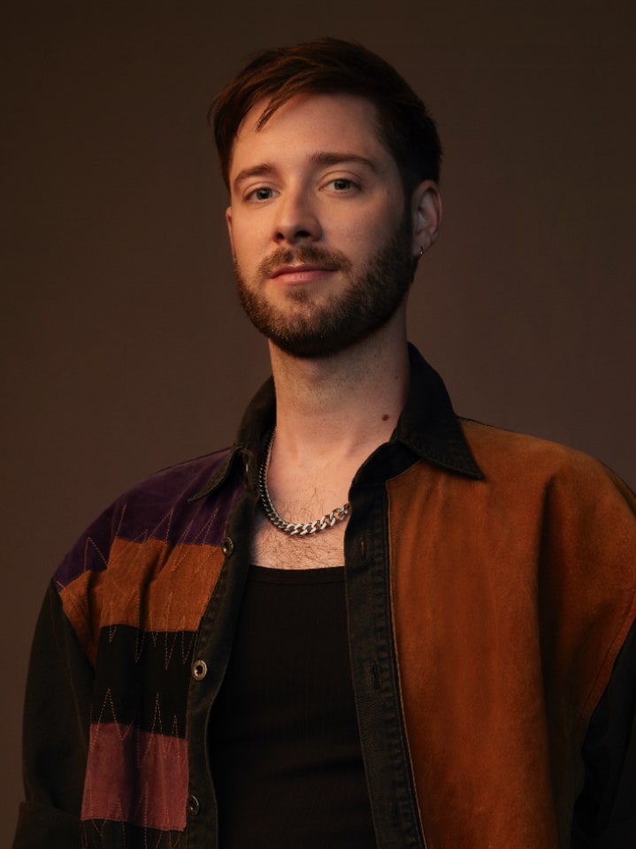 Stephen Dunn the creator of the new Queer as Folk in a diptych with the poster for the show.