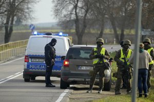 Polish police officers and military staff control cars near the Polish-Belarusian border, that was closed because of a large group of migrants camping in the area on the Belarus side who had tried to illegally push their way into Poland and into the European Union, near Sokolka, Poland, Saturday, Nov. 13, 2021.