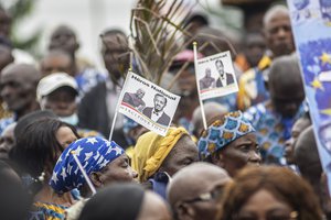 People gather along the road as a military vehicle carries a gold-capped tooth belonging to Democratic Republic of the Congo independence hero Patrice Lumumba to a memorial built in his honour, in Kinshasa Thursday June 30, 2022