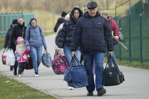 Refugees walk after fleeing the war from neighbouring Ukraine at the border crossing in Medyka, southeastern Poland, Monday, April 11, 2022.