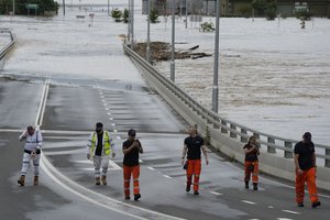 State emergency staff stand near the entrance to the flooded Windsor bridge on the outskirts of Sydney, Australia, Thursday, March 3, 2022