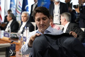 Canada's Prime Minister Justin Trudeau hangs his coat on the back of his chair as he waits for the start of a lunch with the Group of Seven leaders at the Schloss Elmau hotel in Elmau, Germany, Monday, June 27, 2022, during the annual G7 summit.