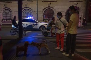 A police car patrols the street as residents gather nearby, Tuesday, May 31, 2022, in Shanghai