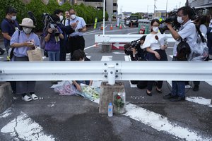 A man places a bouquet of flowers at a makeshift memorial at the scene where the former Prime Minister Shinzo Abe was shot while delivering his speech to support the Liberal Democratic Party's candidate during an election campaign in Nara, Friday, July 8, 2022