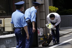 A person with a condolence flower bows toward the residence of Japan's former Prime Minister Shinzo Abe who was assassinated Saturday, July 9, 2022, in Tokyo.