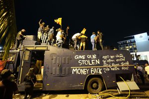 Protesters stand on a vandalised police water canon truck and shout slogans at the entrance to president's official residence in Colombo, Sri Lanka, Saturday, July 9, 2022.