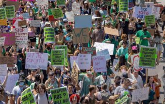 A crowd of people hold signs protesting the Supreme Court's decision to take away abortion rights.