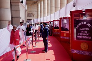 An Indian lawmaker waves as he comes out after casting his vote during India's president election at the Parliament House in New Delhi, Monday, July 18, 2022.